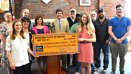 Mark C. Poloncarz stands with supports presenting a check